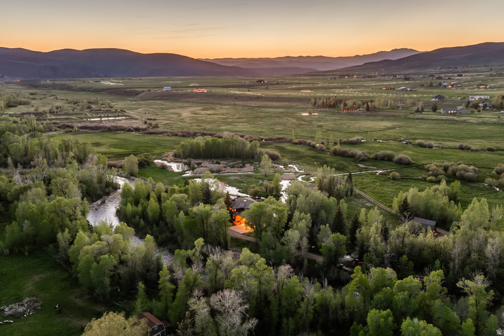 Expansive landscape featuring a winding river, verdant trees, and distant mountains