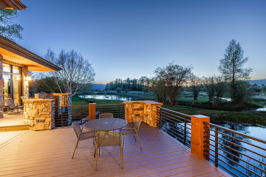 Expansive outdoor deck with composite decking, stone pillars, and metal railing overlooking a tranquil body of water