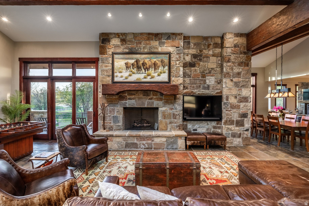 Spacious living area featuring a floor-to-ceiling stone fireplace, exposed wood beams, and recessed lighting