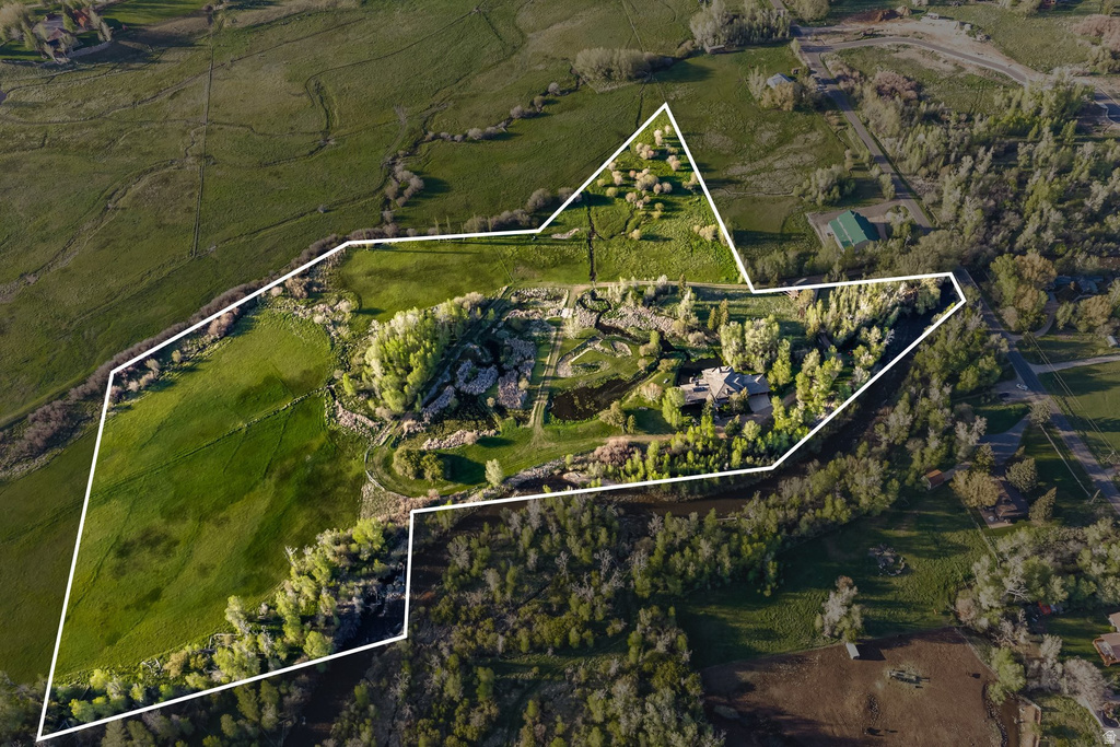 Expansive land parcel featuring varied terrain including open green fields and wooded areas