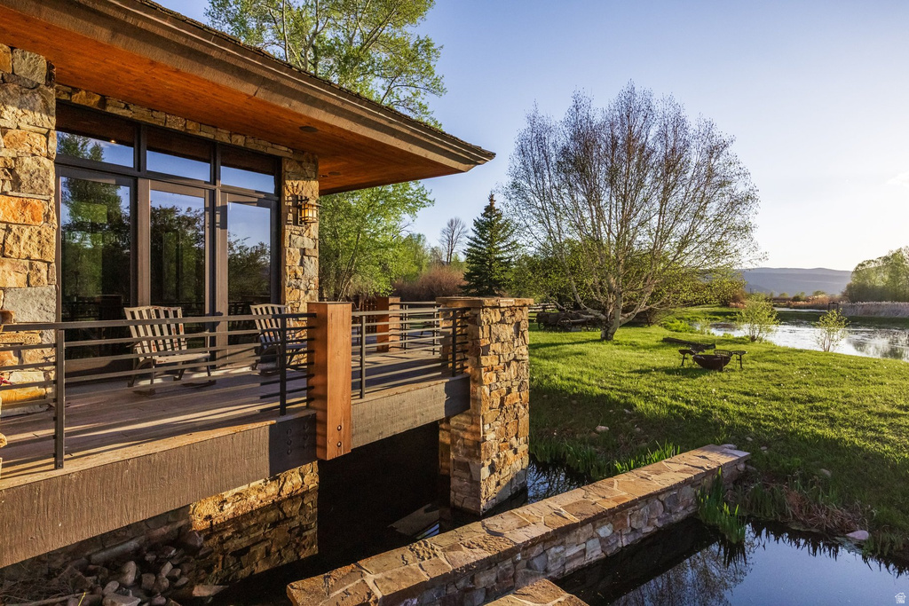 Stone-clad exterior featuring a wood-finish soffit and a dark-framed glass door opening onto a private deck