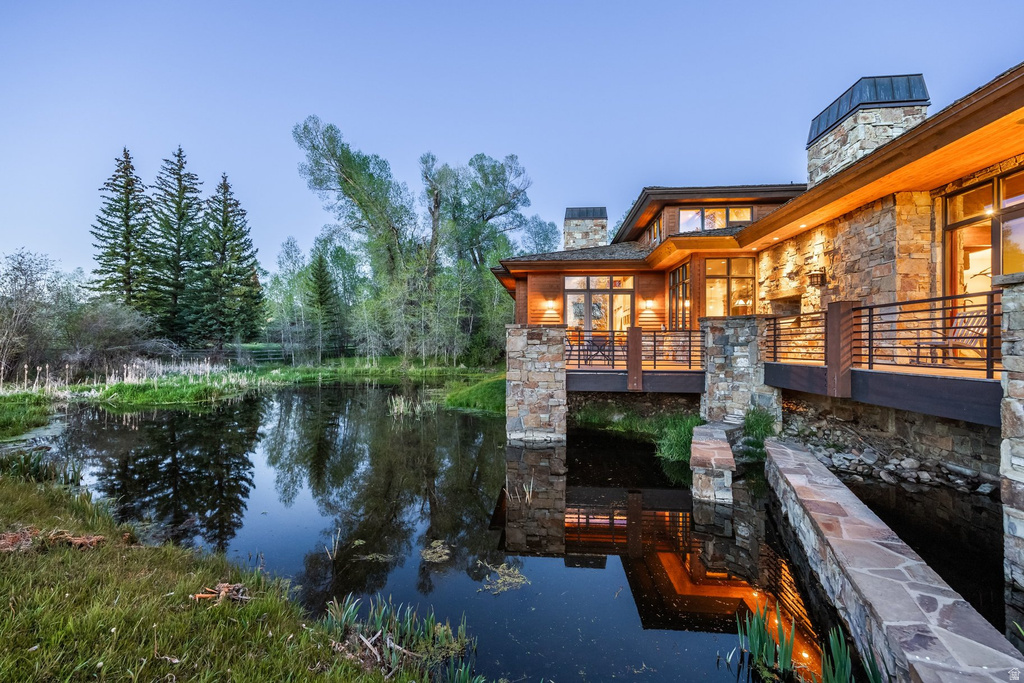 Stone and wood-clad exterior with multiple balconies overlooking a tranquil pond