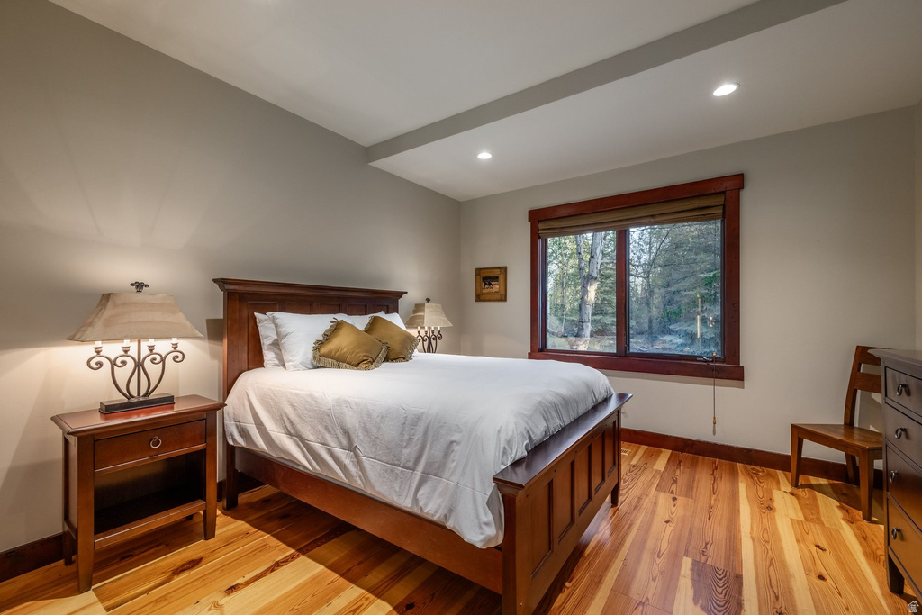 Bedroom featuring wood-finish flooring, recessed lighting, and a large window with wood trim