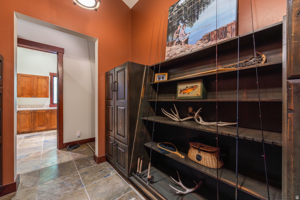 Built-in dark wood shelving and cabinetry with a stone tile floor