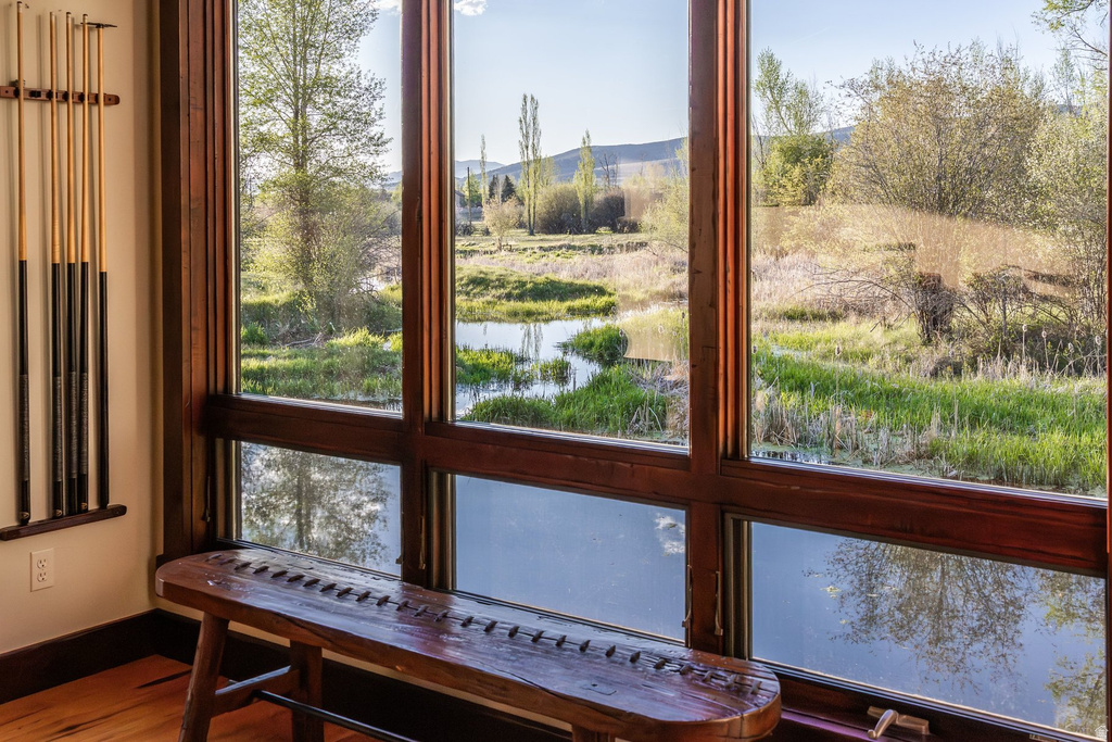 Expansive multi-pane window system with dark wood frames, offering extensive natural light and verdant outdoor scenery