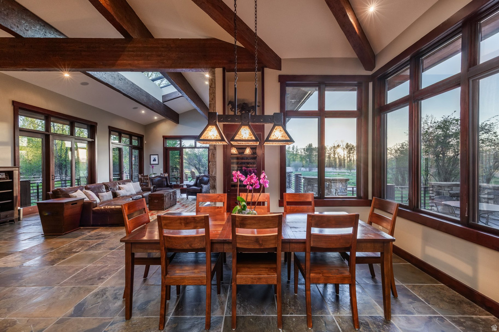 Spacious dining area featuring stone tile flooring and exposed wood ceiling beams