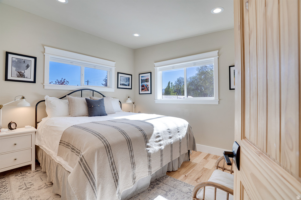 Bedroom featuring wood-finish flooring, recessed lighting, and bright windows with white trim