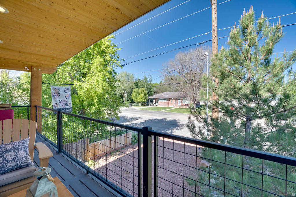 Upper-level balcony featuring a wood-finish ceiling, composite decking, and contemporary metal grid railings