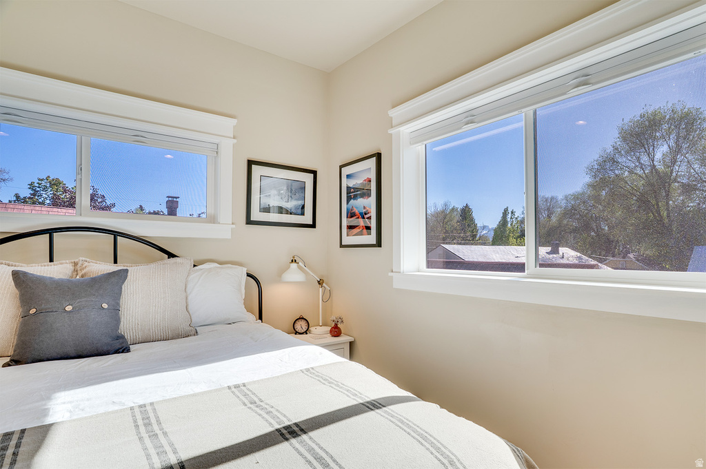 Spacious bedroom featuring multiple windows with clean white trim, a black metal bed frame, and light neutral wall colors