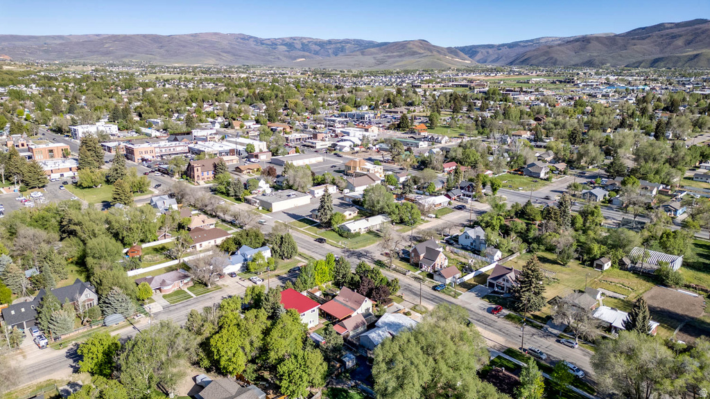 Expansive aerial perspective showcasing a residential neighborhood with established trees and a distant mountainous backdrop