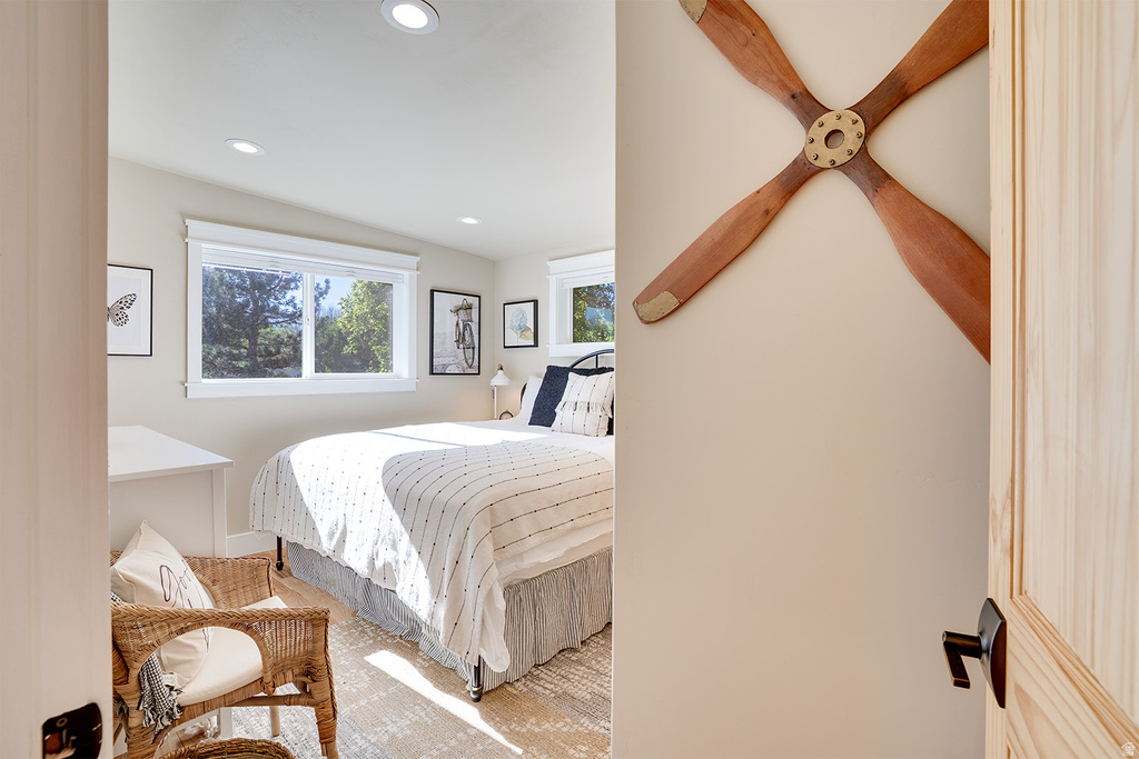 Light-filled bedroom featuring recessed lighting, multiple windows with white trim, and light wood-finish flooring
