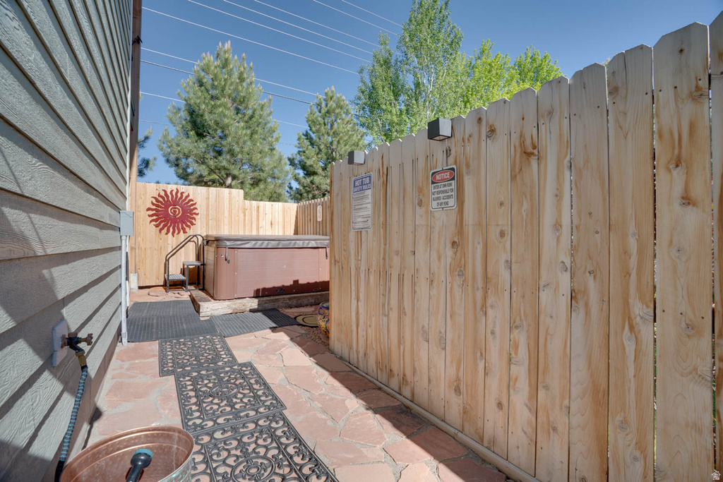Private outdoor area featuring a hot tub with adjacent steps and handrail, surrounded by a wood privacy fence
