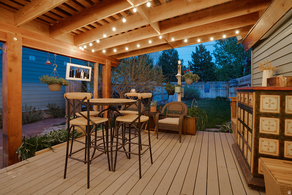 Covered deck with light-toned plank flooring and exposed wood beam ceiling
