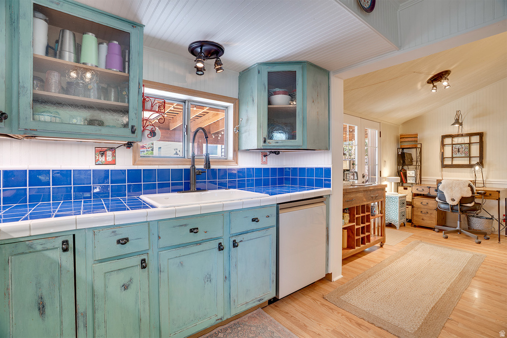 Kitchen featuring distressed teal cabinetry, square blue tile backsplash, a white tile countertop, and a white drop-in sink with a black gooseneck faucet