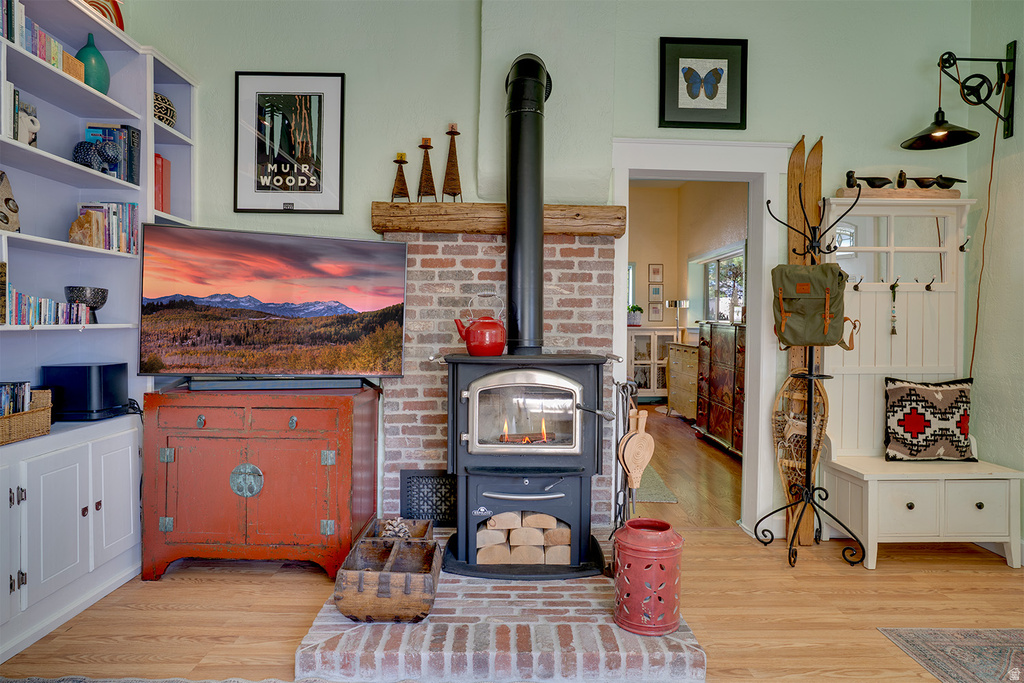Brick fireplace featuring a wood-burning stove, solid wood mantel, and a brick hearth