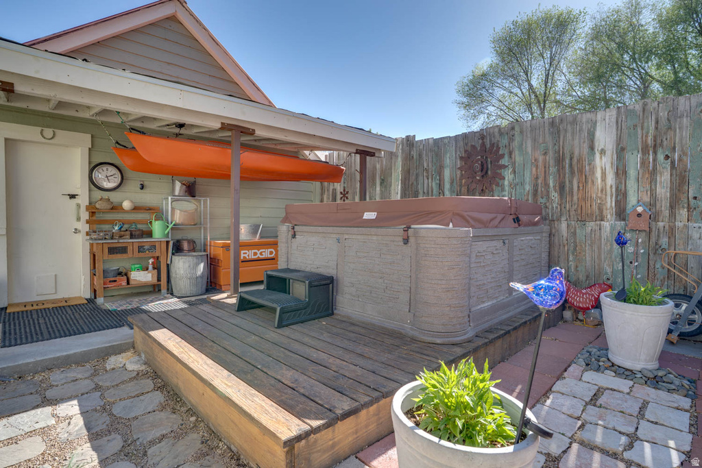 Outdoor patio featuring a built-in hot tub, wood-finish decking, and a stone paver pathway