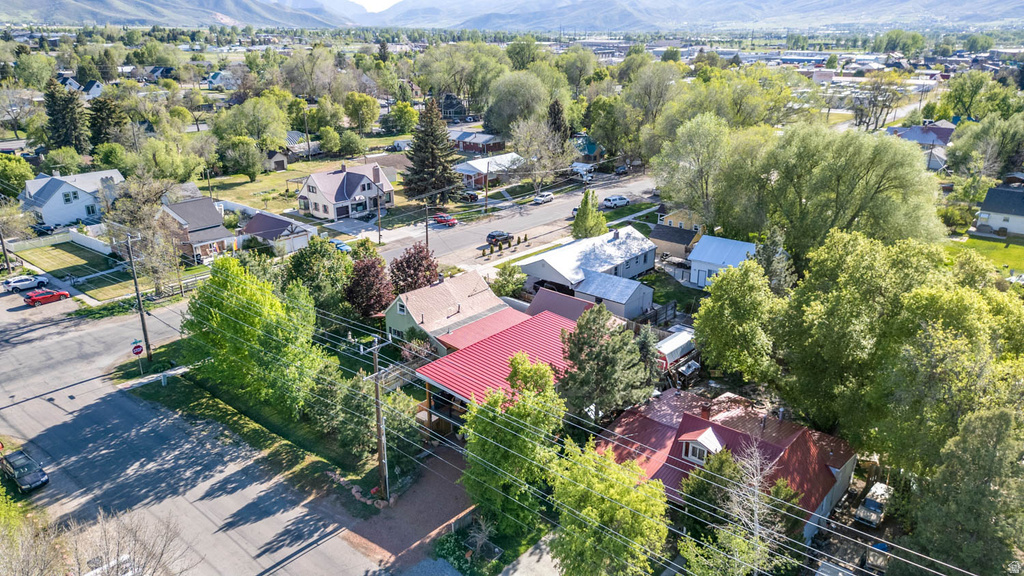 Aerial view featuring residential properties with mature trees and mountain scenery