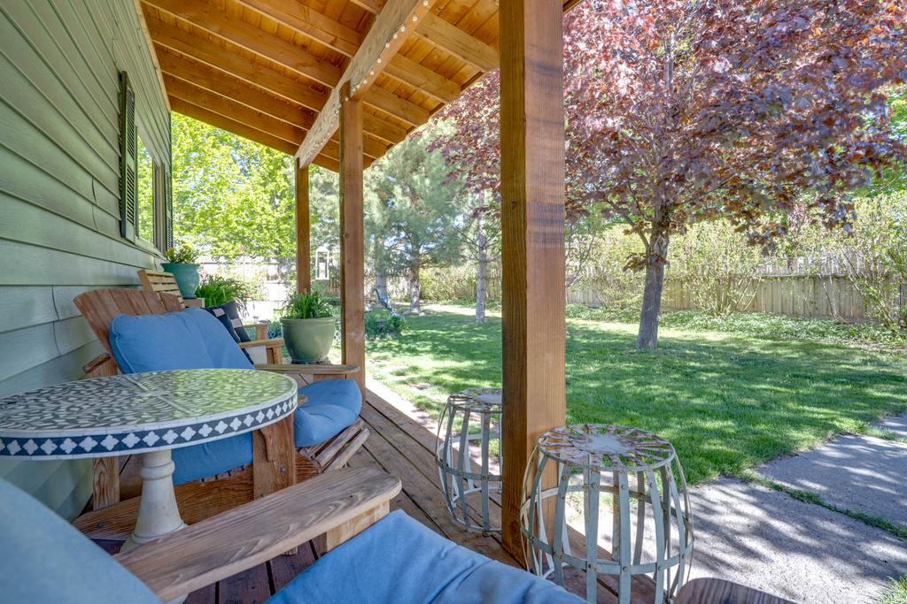 Covered wood-finish porch featuring exposed wood beams, siding exterior, and a manicured lawn