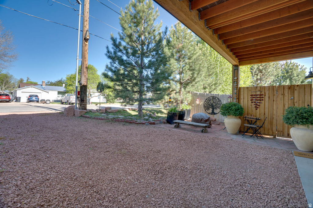 Covered outdoor patio with exposed wood ceiling beams, featuring a wood privacy screen and gravel ground covering