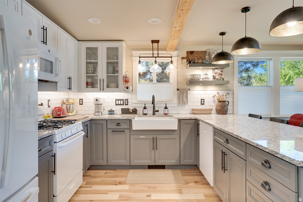 Kitchen featuring granite countertops, a farmhouse sink, stainless steel appliances, wood-finish flooring, and pendant lighting