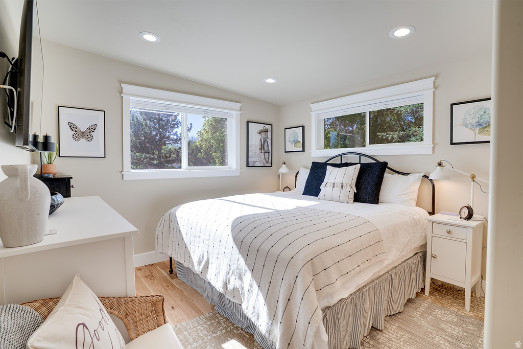 Bedroom featuring two large windows, recessed ceiling lighting, light wood-finish flooring, and white baseboards