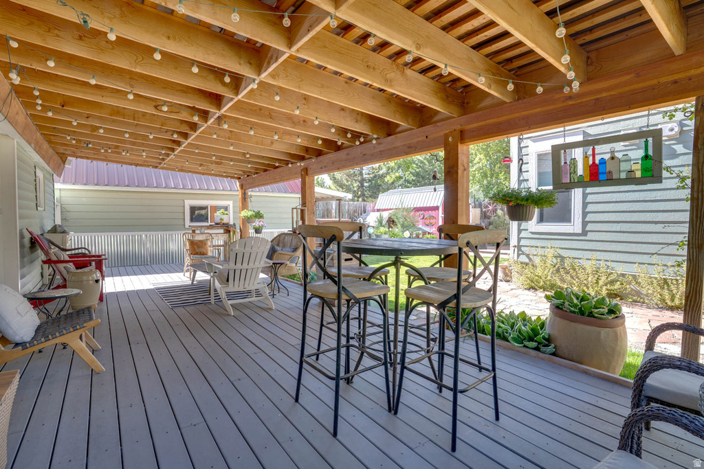 Expansive covered deck featuring a light grey wood-finish surface and exposed wood beam ceiling