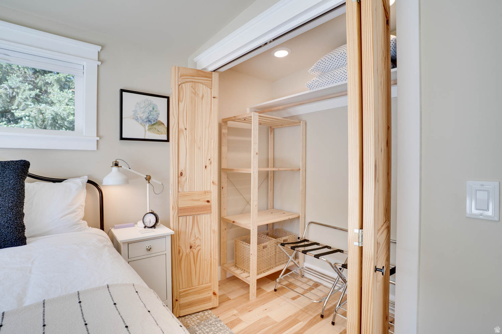 Closet with natural wood bifold doors, integrated shelving, and wood-finish flooring