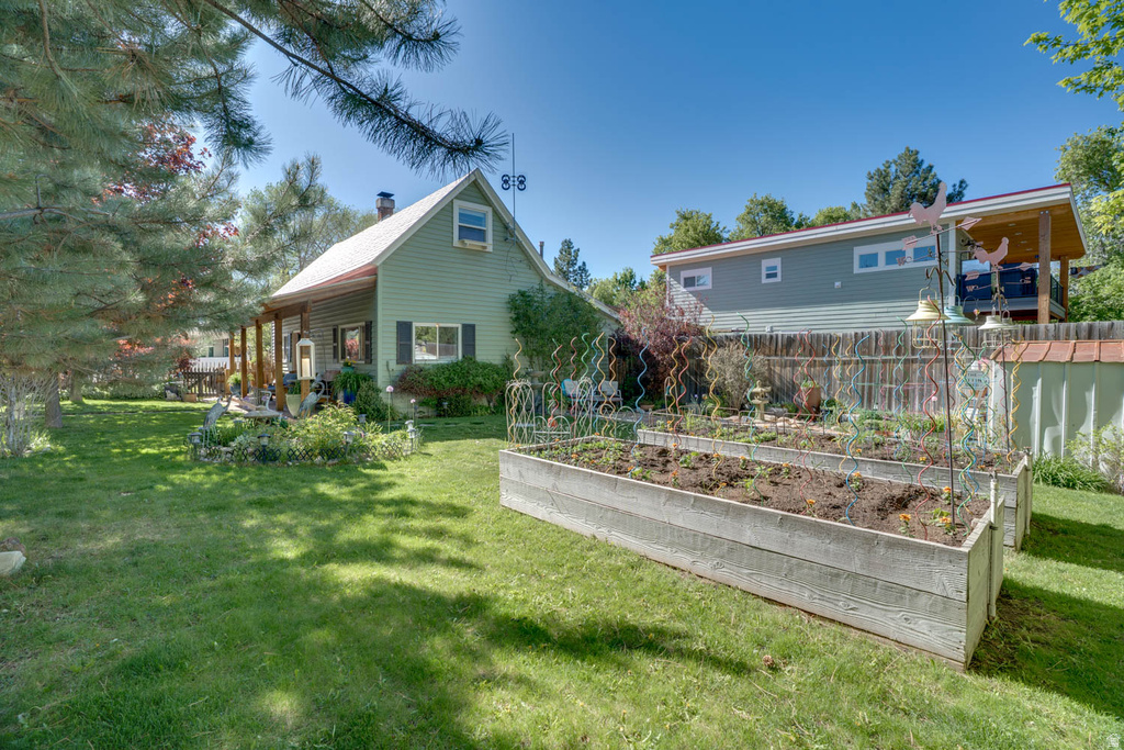 Expansive green space featuring two large raised garden beds, a fenced perimeter, and mature trees