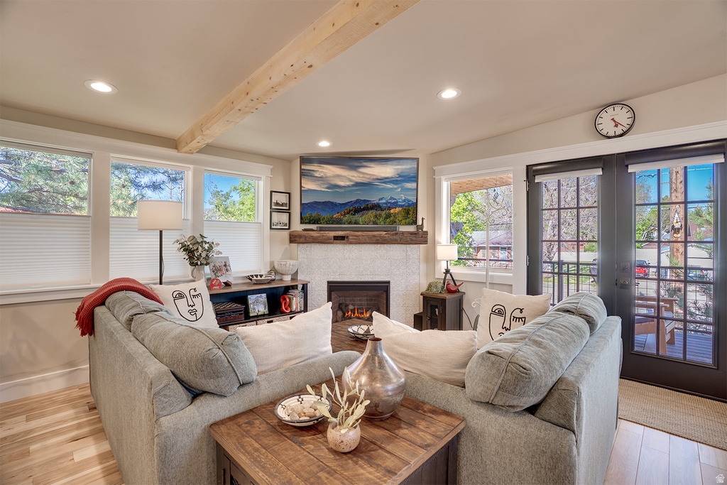 Living area featuring wood-finish flooring, a white brick fireplace with a wood mantle, and exposed ceiling beam