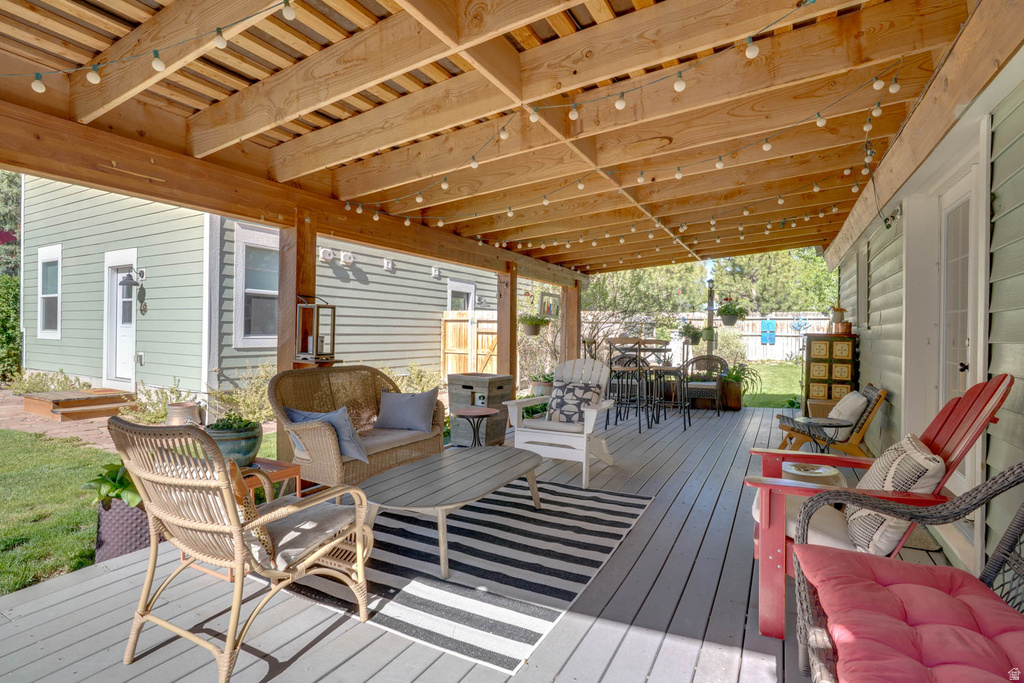 Expansive covered deck featuring a natural wood beam ceiling, string lighting, and gray plank flooring