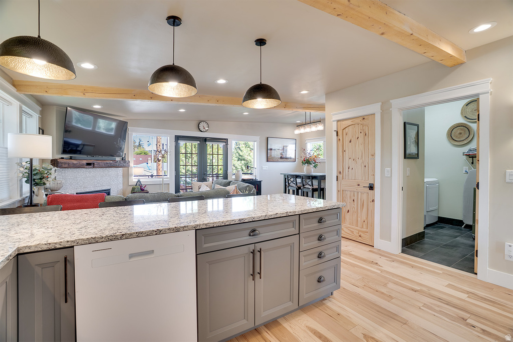 Kitchen island featuring a granite countertop, integrated dishwasher, and gray cabinetry with black hardware