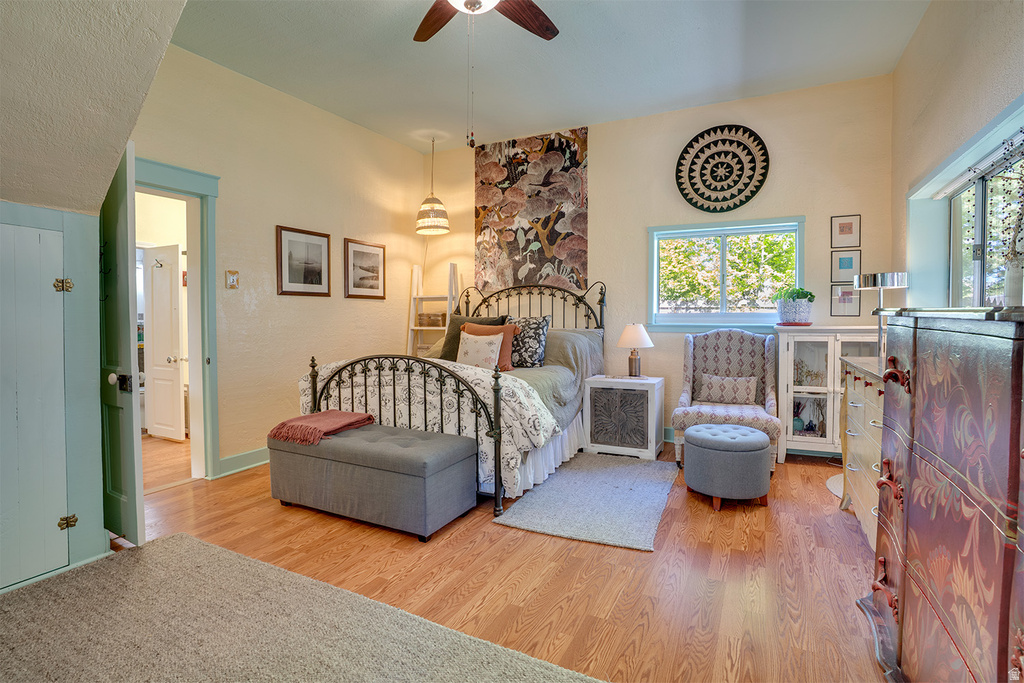 Hardwood flooring throughout featuring a ceiling fan, recessed window, and light-colored walls
