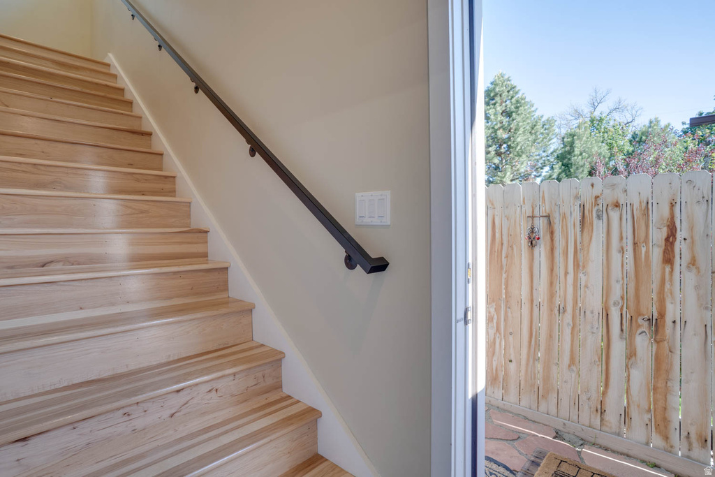 Wood-finish staircase featuring a contrasting metal handrail, light beige wall paint, and white trim