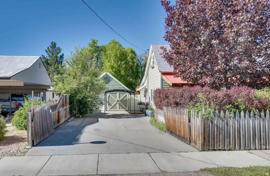 Concrete driveway with a detached garage featuring carriage-style doors, wood siding, and an architectural gable vent