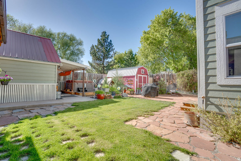 Expansive backyard featuring a green lawn, flagstone pathway, and a red garden shed