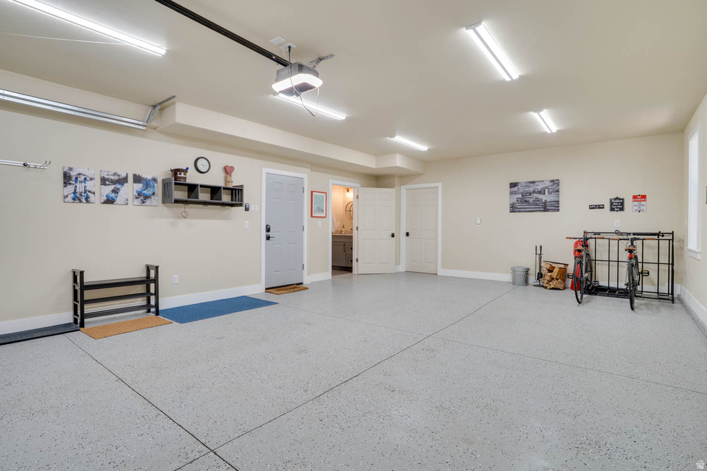 Spacious garage featuring a light gray epoxy floor, ample overhead lighting, and direct access to an interior room