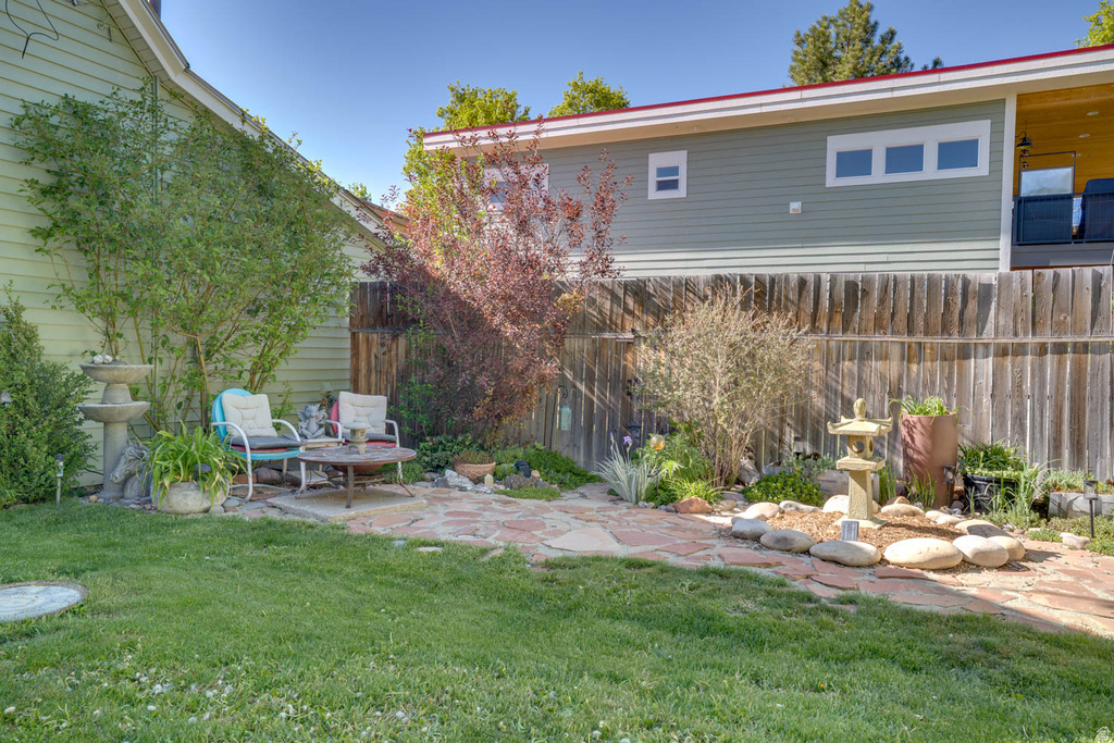 Expansive backyard featuring a stone patio, manicured lawn, and mature trees