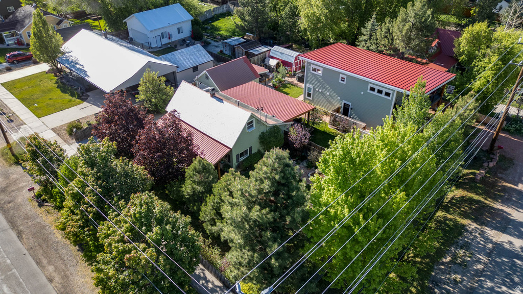 Aerial view showcasing two residential structures featuring metal roofing and mature landscaping