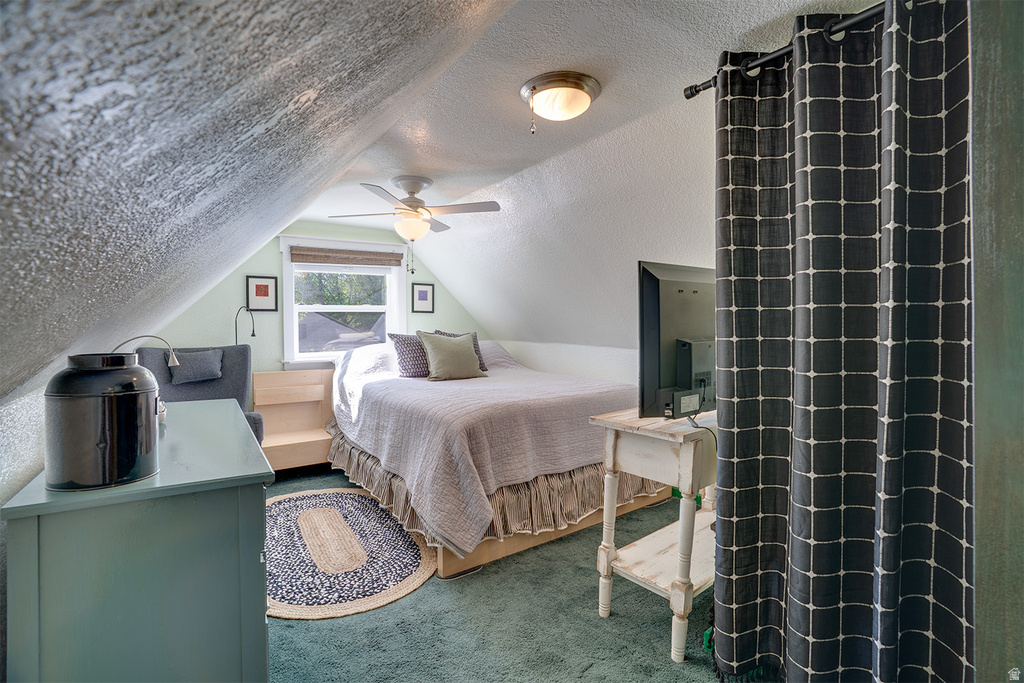 Attic space featuring sloped ceilings, a window with exterior views, and a ceiling fan