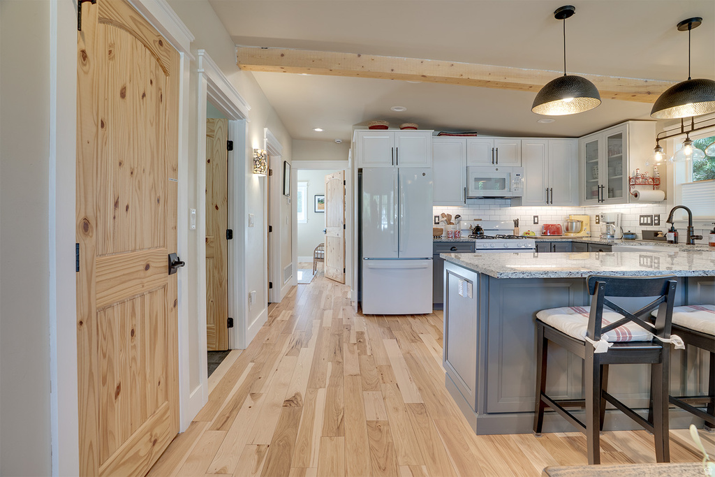 Open-concept kitchen featuring two-tone cabinetry, a central island with countertop seating, and light wood-finish flooring