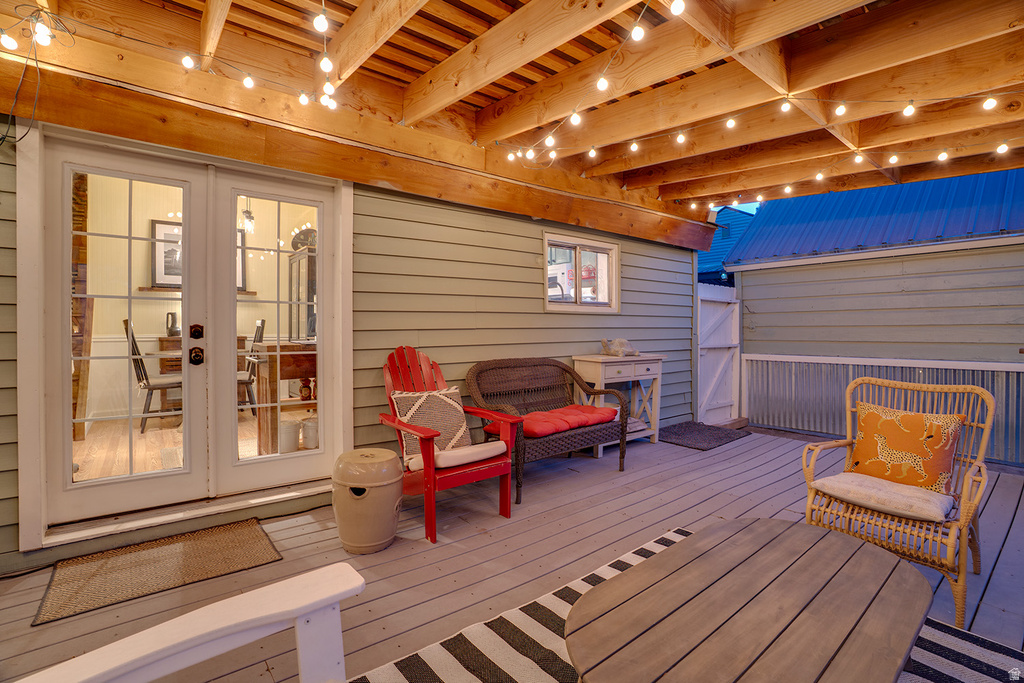 Spacious outdoor deck with light gray decking, exposed wood beam ceiling, and string lighting