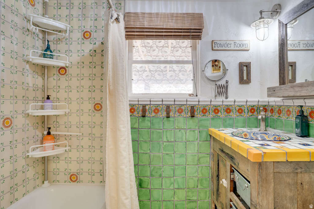 Bathroom featuring decorative ceramic tile walls and a wood-finish vanity with a tiled countertop