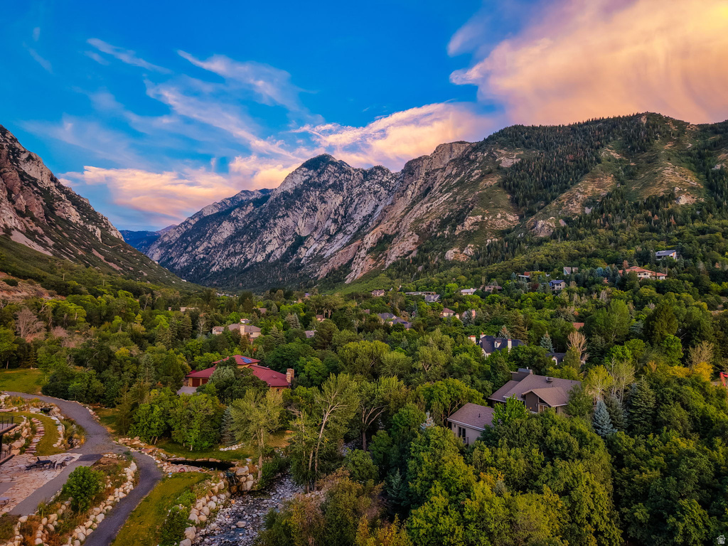 Expansive mountain scenery with a verdant valley, established residential properties, mature tree coverage, and a meandering natural water feature