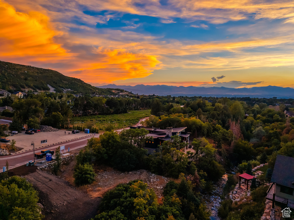 Expansive landscape featuring distant mountains, lush green trees, and a visible property with a red-roofed structure