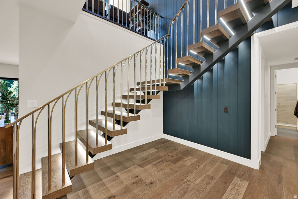 Floating wood-finish staircase with integrated lighting, custom metal railings, and a vertical plank accent wall