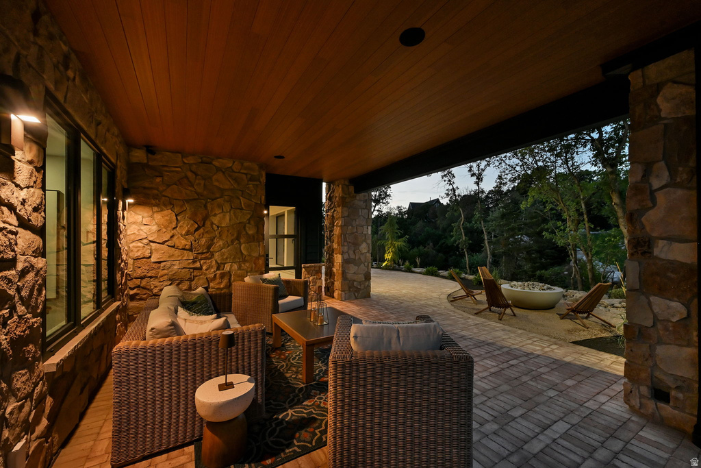 Covered outdoor patio featuring stone walls, wood-finish ceiling, paver flooring, and recessed lighting