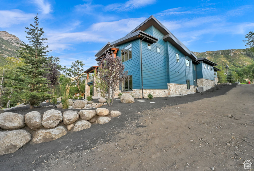 Modern exterior featuring blue horizontal siding and a stone foundation