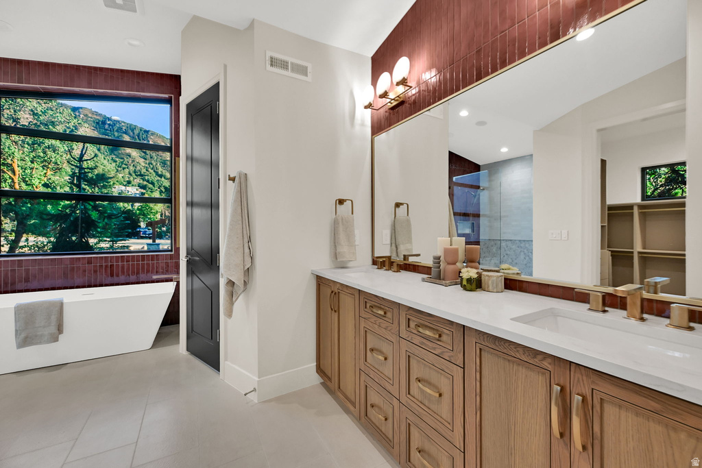 Spacious bathroom featuring a freestanding tub, large picture window, dual vanity with undermount sinks, wood-finish cabinetry, and a full-width mirror
