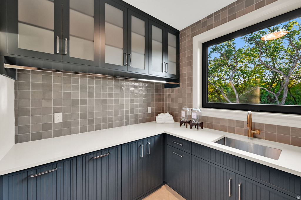 Corner sink area featuring a stainless steel sink, brass faucet, and white countertop