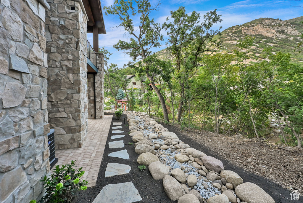 Stone exterior with a paver walkway and natural rock landscaping